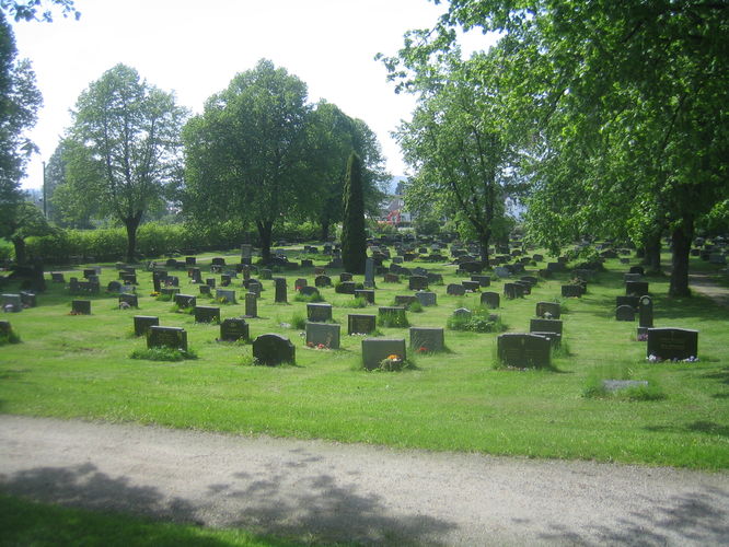 Nedre kirkegård med gravminner. Grønt grass og mange grønne trær