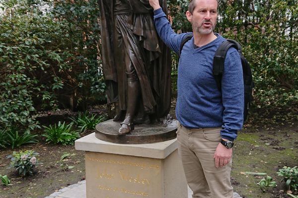 Prest Dag Martin Østevold viser frem en statue av John Wesley